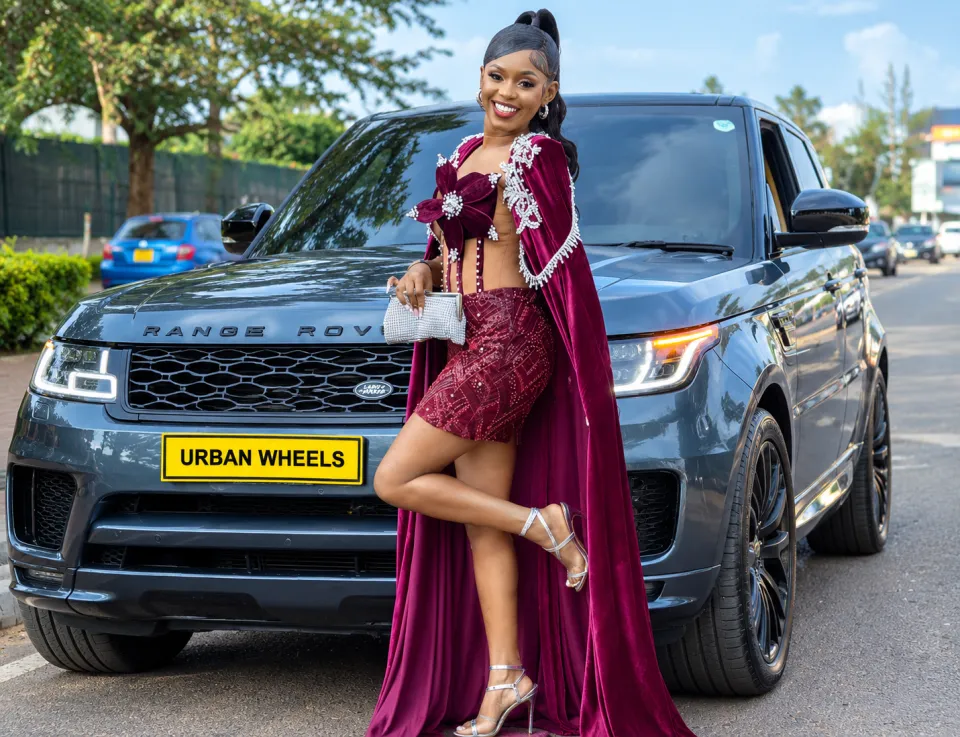Guest in a burgundy velvet cape posing in front of an Urban Wheels Range Rover